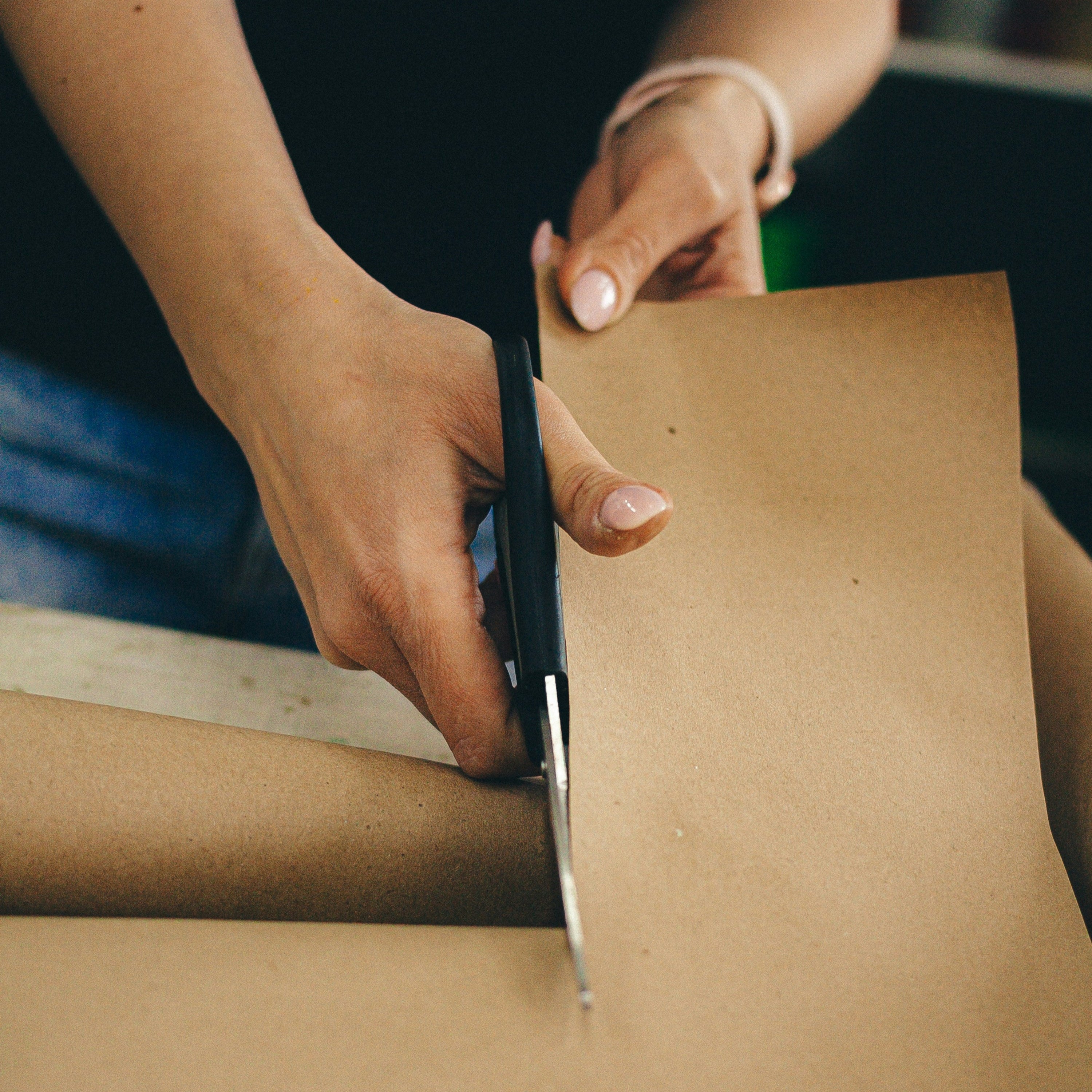Woman cutting brown packing paper with scissors