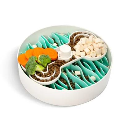 A green wave puzzle feeder bowl with kibble and vegetables